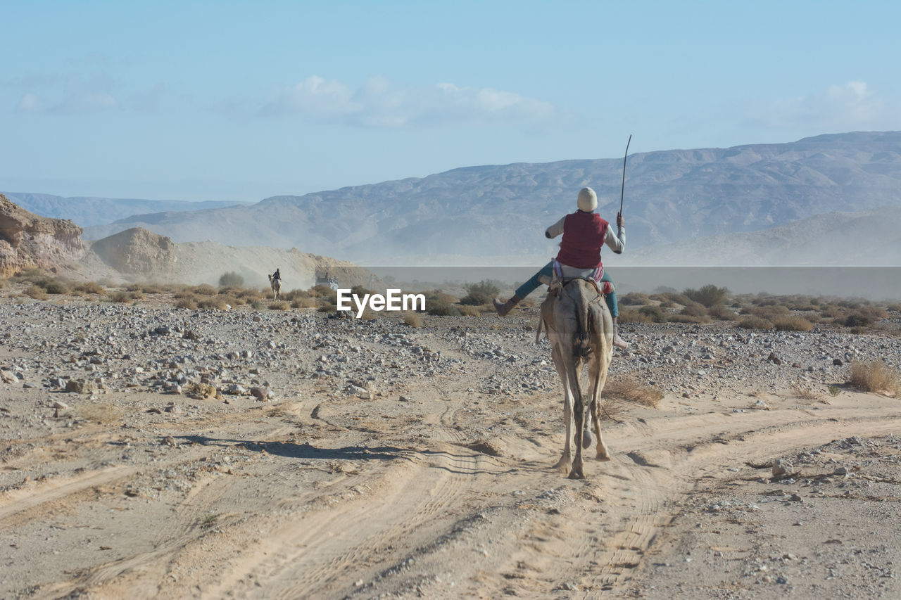 MAN RIDING HORSE IN DESERT