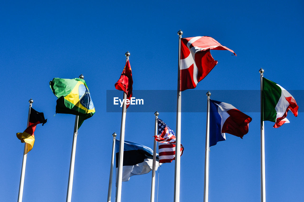 Low angle view of flags flag against clear blue sky