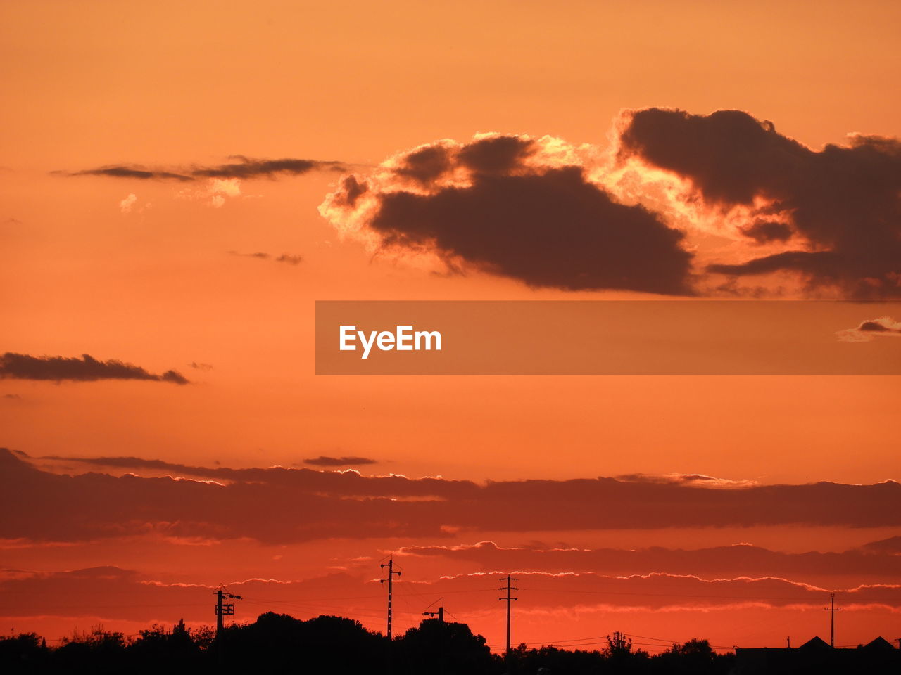 SILHOUETTE OF ELECTRICITY PYLON AGAINST DRAMATIC SKY