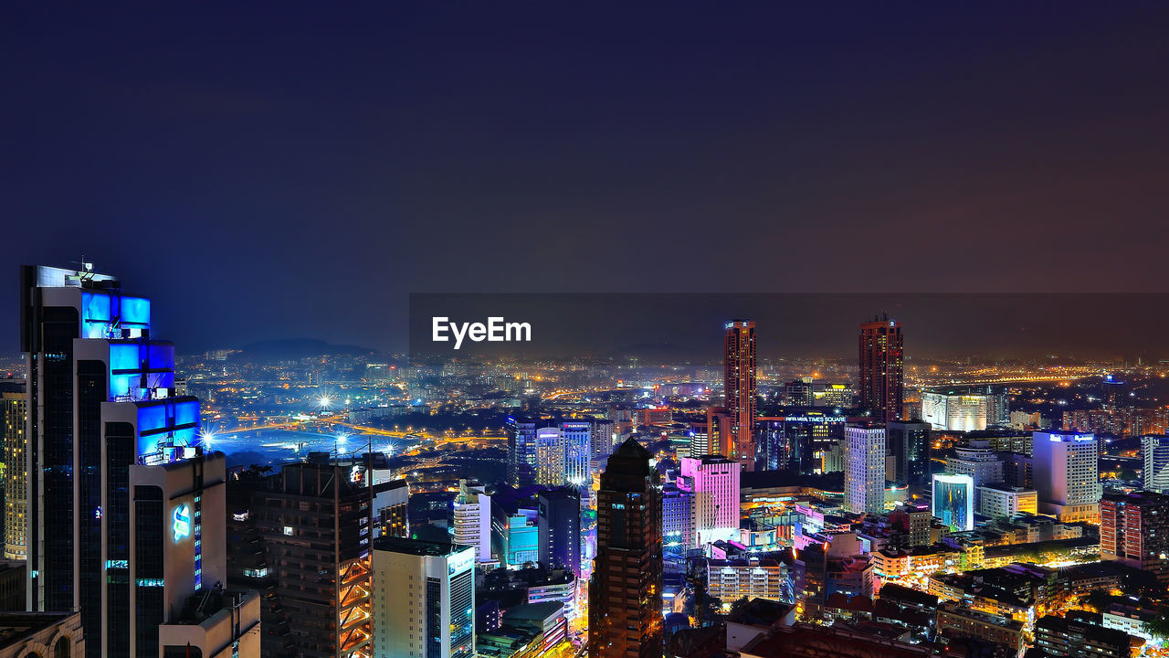 High angle view of illuminated buildings against sky at night