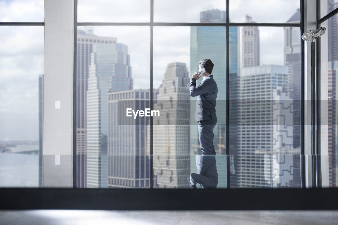 Businessman on the phone in city office looking out of window