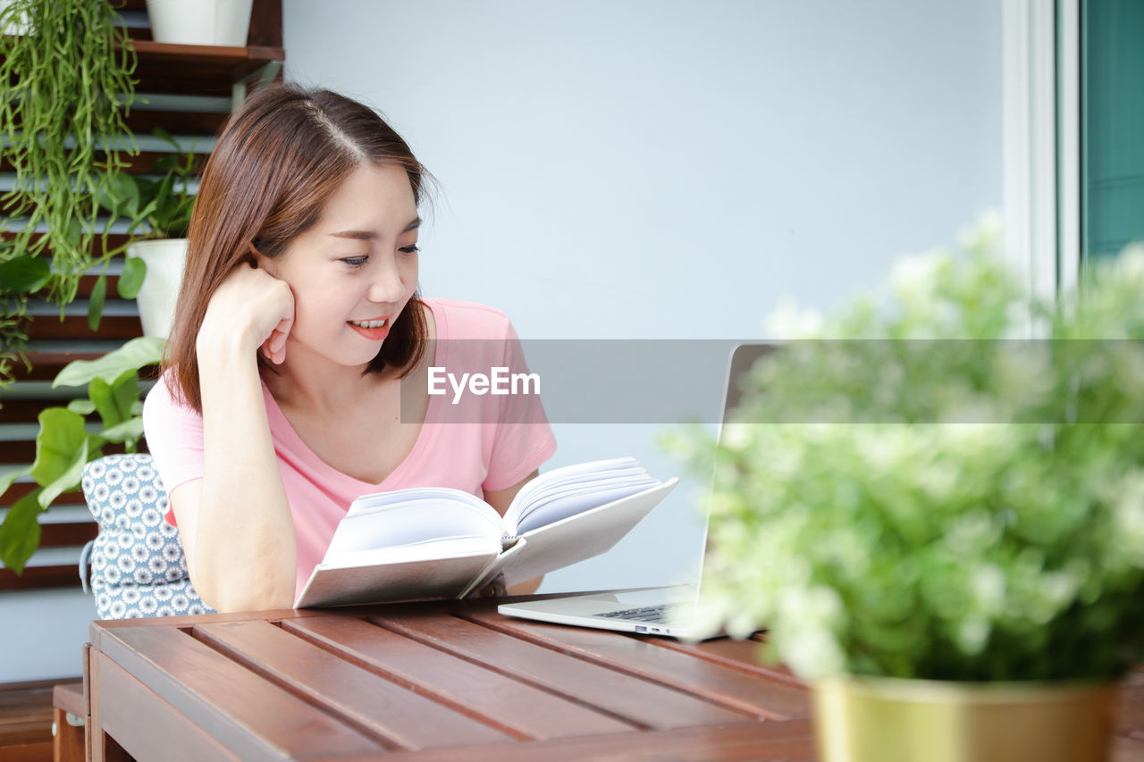 young woman using mobile phone while sitting at home