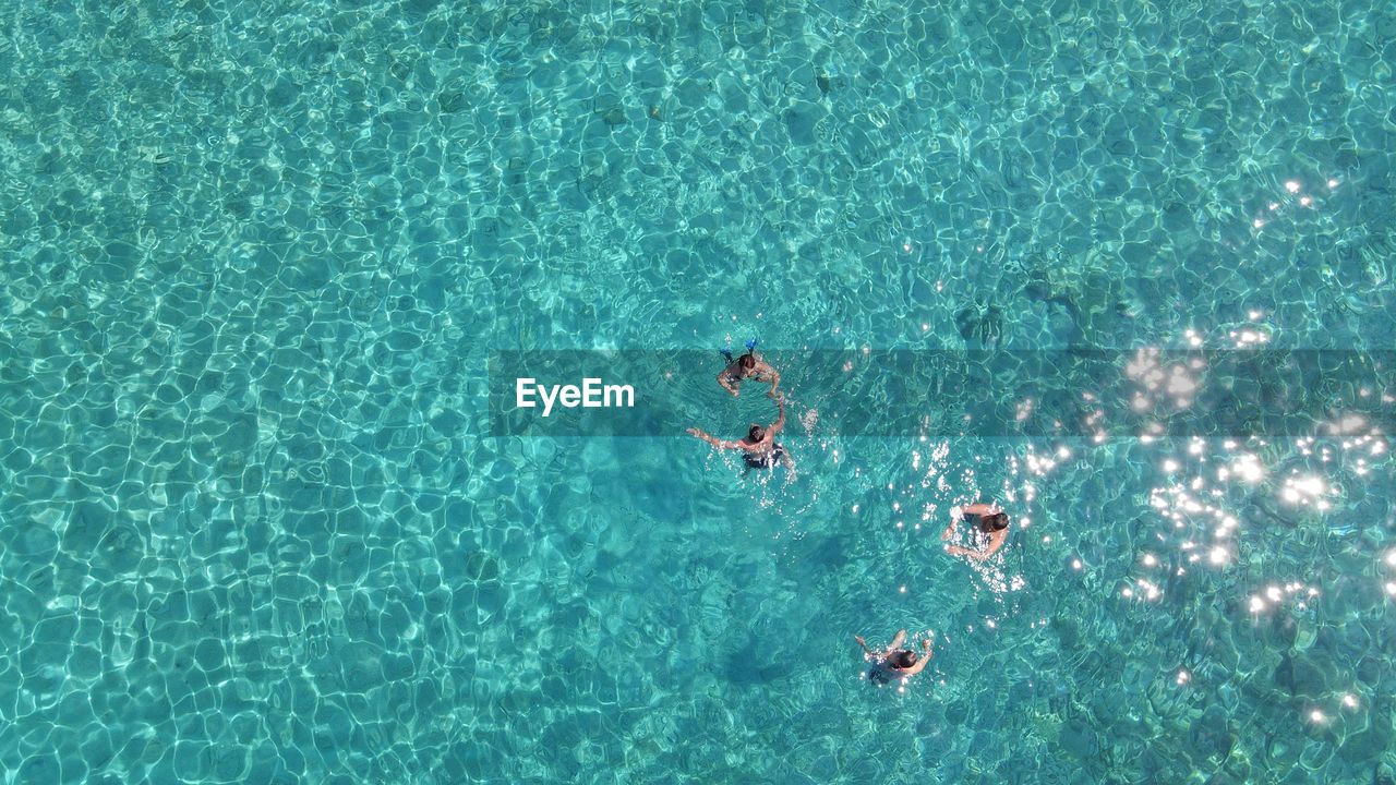 HIGH ANGLE VIEW OF FRIENDS SWIMMING IN POOL