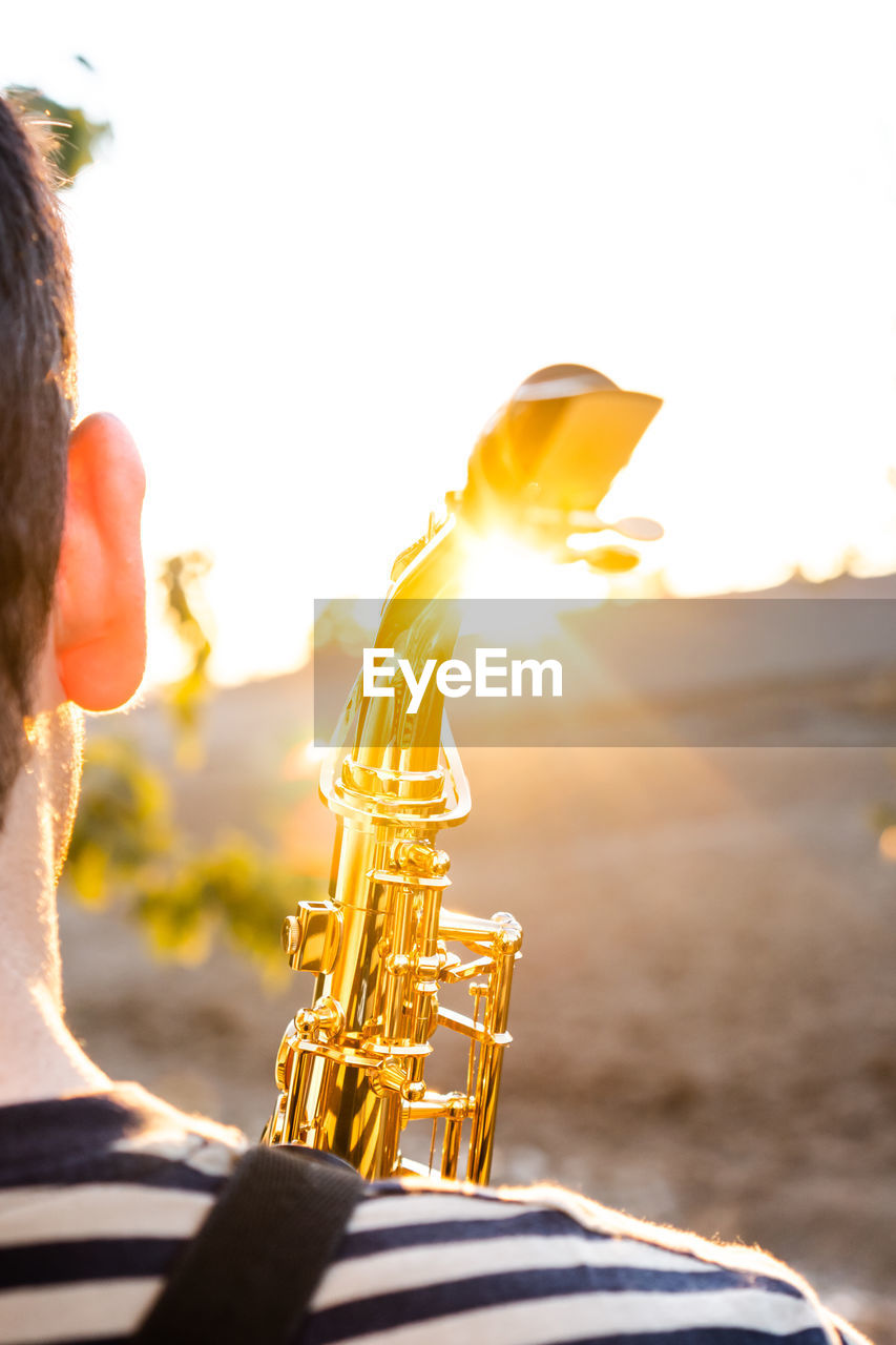 MIDSECTION OF MAN PLAYING GUITAR AT SUNSET