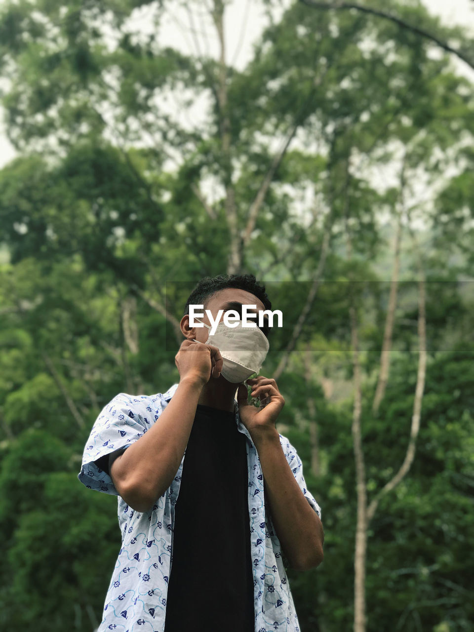 Man wearing protective face mask against trees