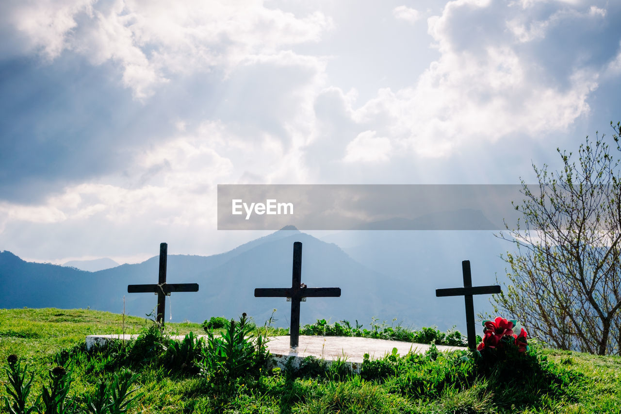 grave, cross, cemetery, religion, sky, belief, cloud, spirituality, nature, hill, crucifix, cross shape, plant, catholicism, grass, symbol, religious item, rural area, no people, landscape, place of worship, death, environment, tombstone, sunlight, beauty in nature, sadness, tranquility, stone, outdoors, day, memorial, land, flower, grief, scenics - nature, idyllic, architecture, cloudscape, morning, emotion, tranquil scene, tree, horizon, travel destinations, religious equipment