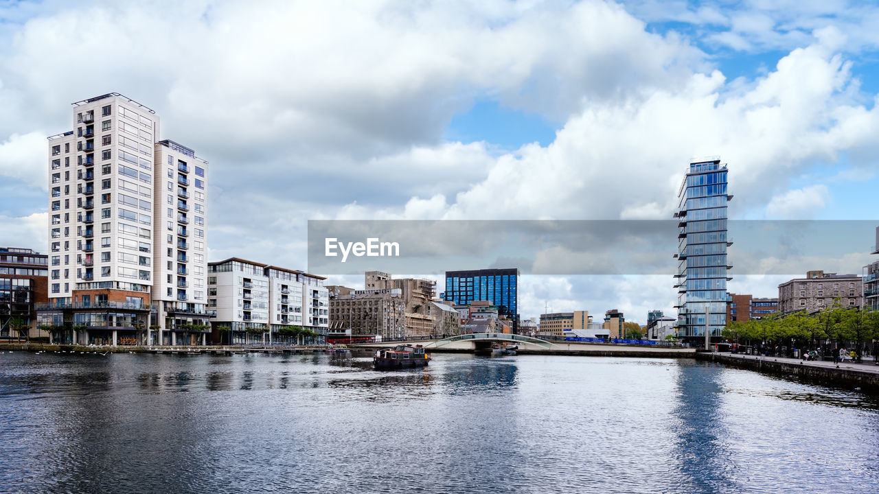 RIVER BY BUILDINGS AGAINST SKY