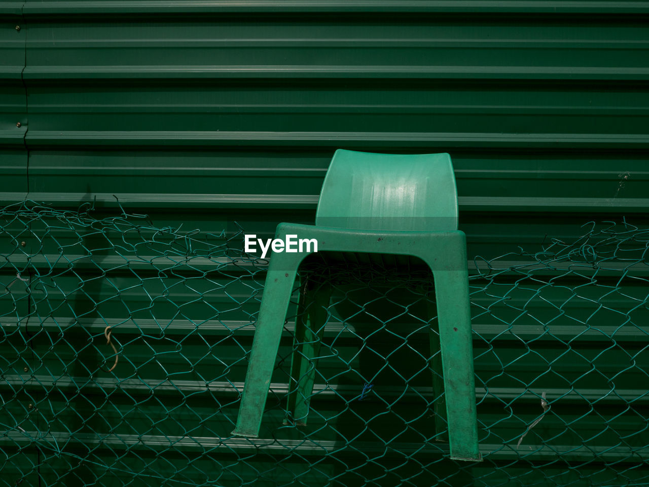Close-up of plastic chair on chainlink fence