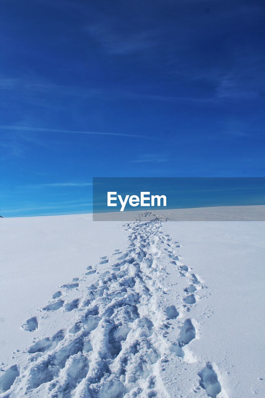 Snow covered land against blue sky