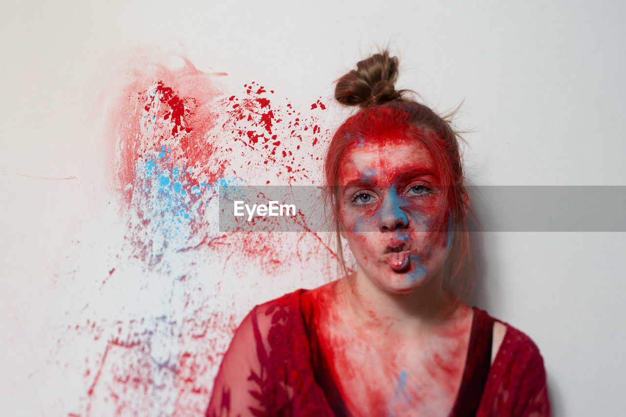 Portrait of teenage girl with powder paint making face against white background