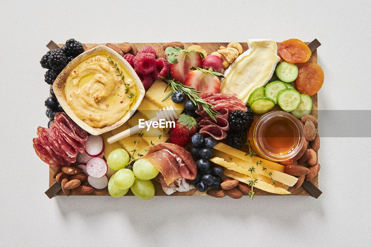 food and drink, food, healthy eating, fruit, freshness, vegetable, studio shot, wellbeing, indoors, cheese, directly above, produce, dairy, variation, olive, still life, high angle view, no people, grape, meal, dish, slice, appetizer, white background, cuisine, ingredient, platter, snack