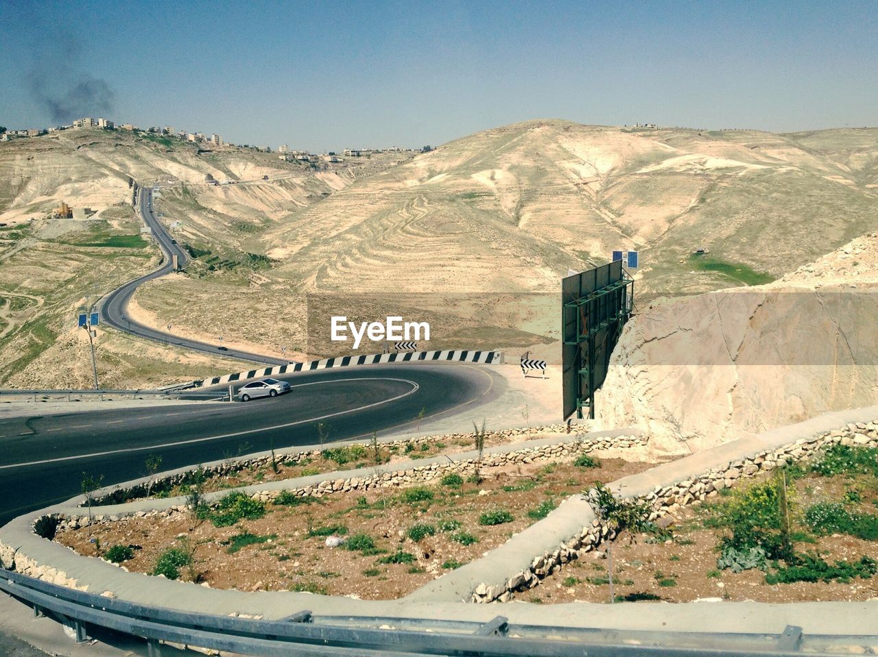 Scenic view of road by mountains against clear sky