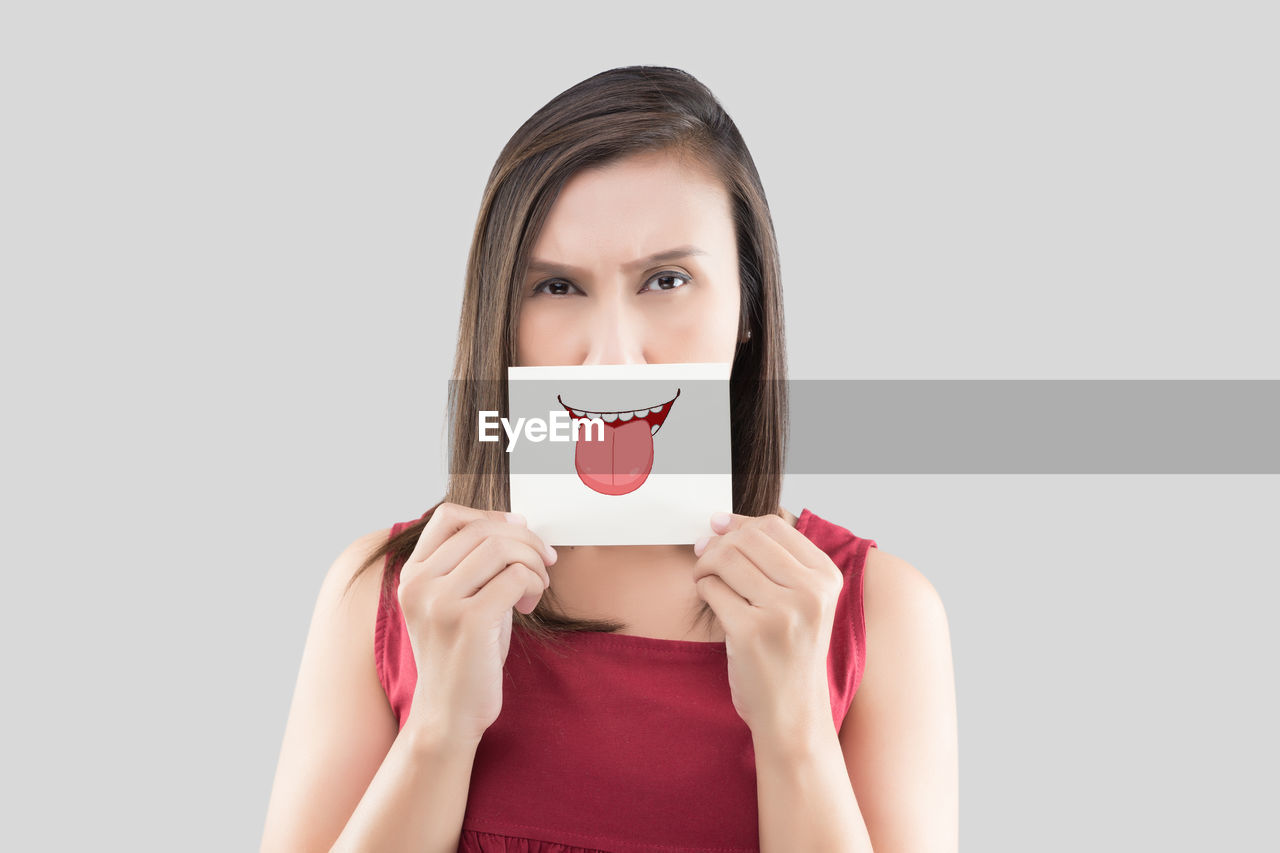 Optical illusion of woman sticking out tongue against gray background