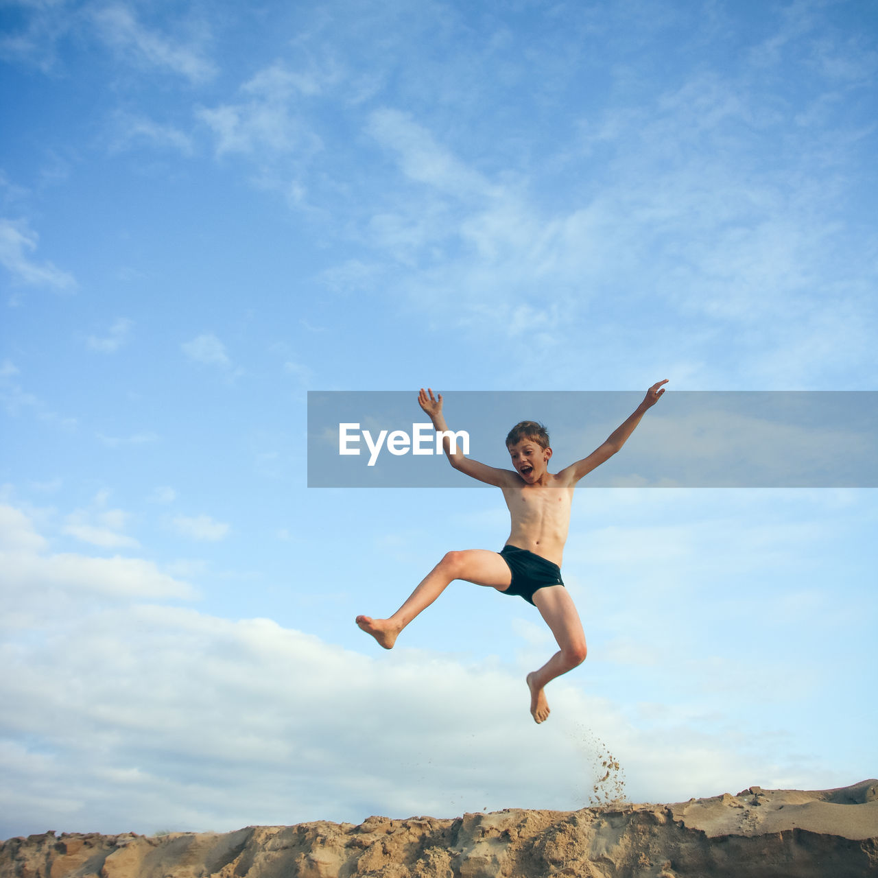 Low angle view of boy jumping against sky