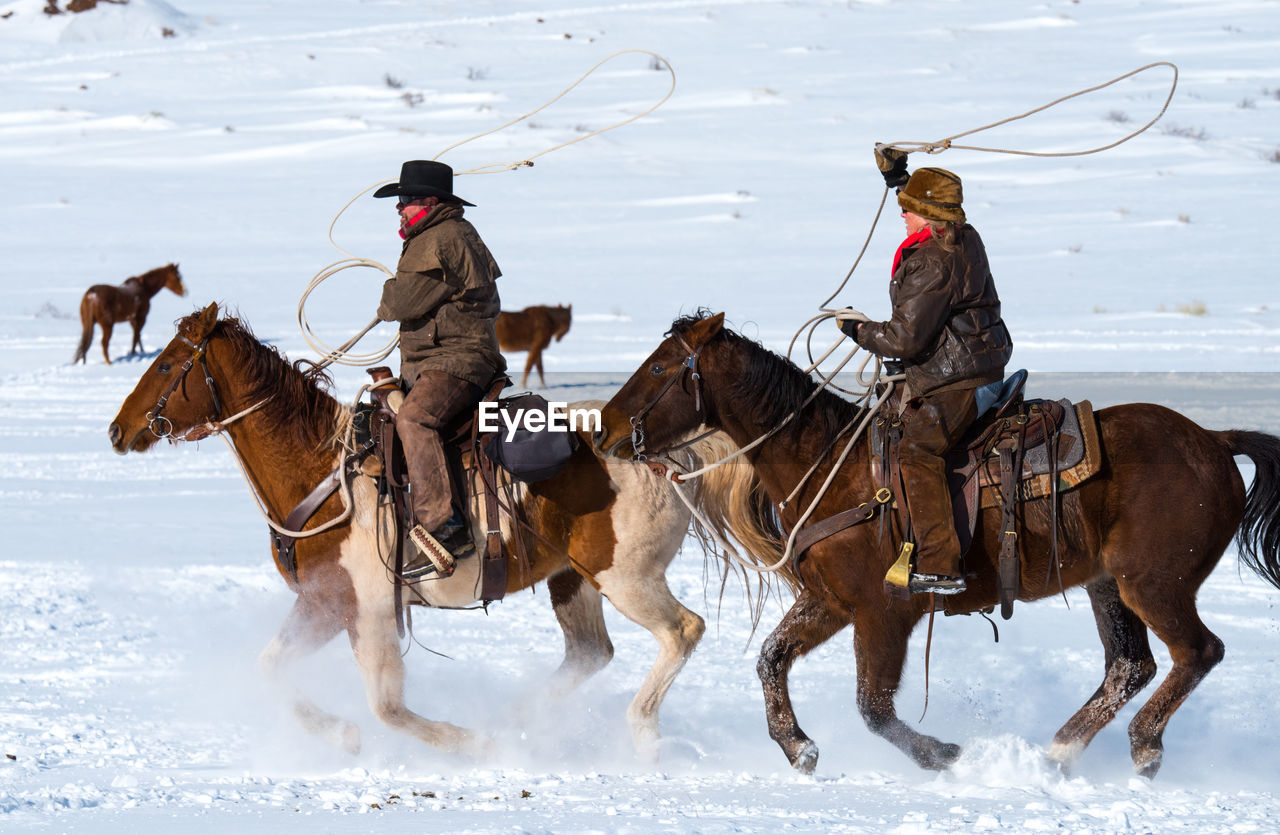 People riding horses on snowy land