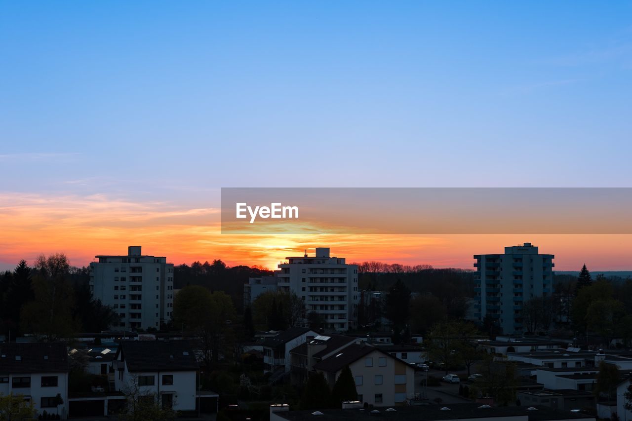 HIGH ANGLE VIEW OF CITYSCAPE AGAINST CLOUDY SKY DURING SUNSET