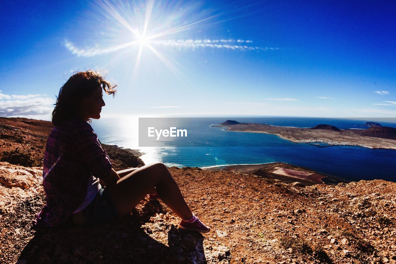 Full length of woman on mountain by sea against sky on sunny day