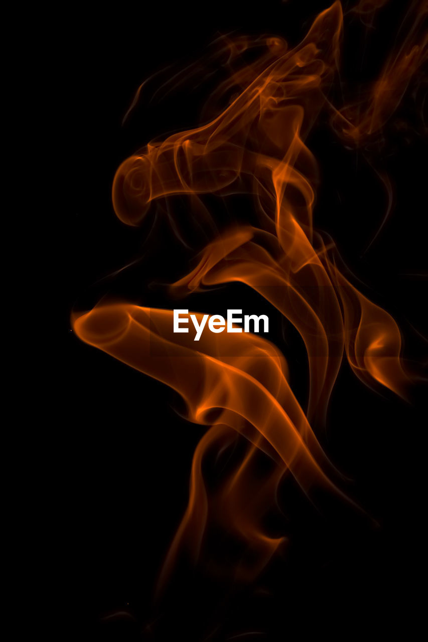 Close-up of orange smoke against black background