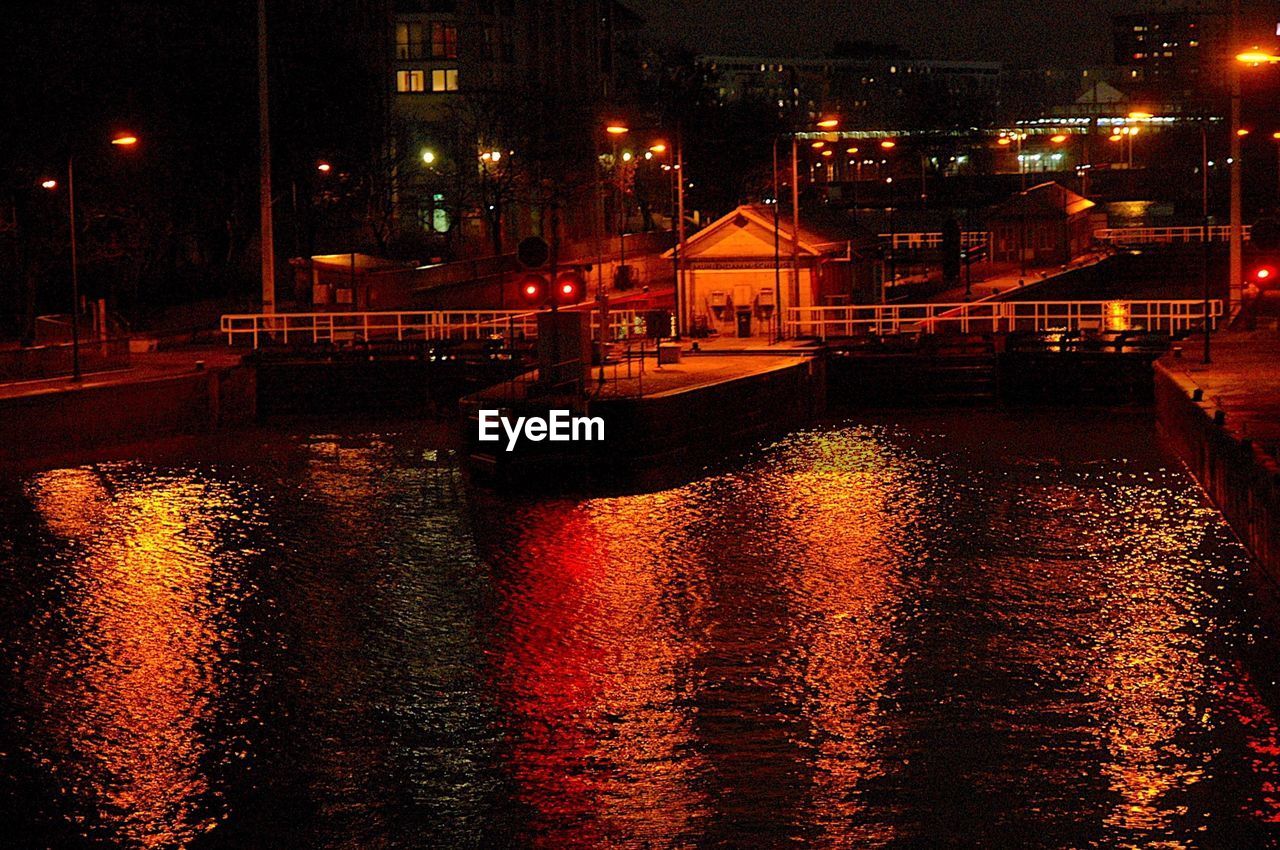 ILLUMINATED CITY BY RIVER AGAINST SKY