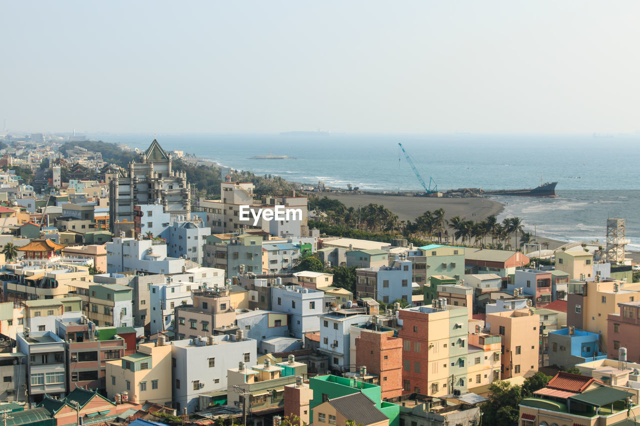 High angle view of buildings by sea against clear sky