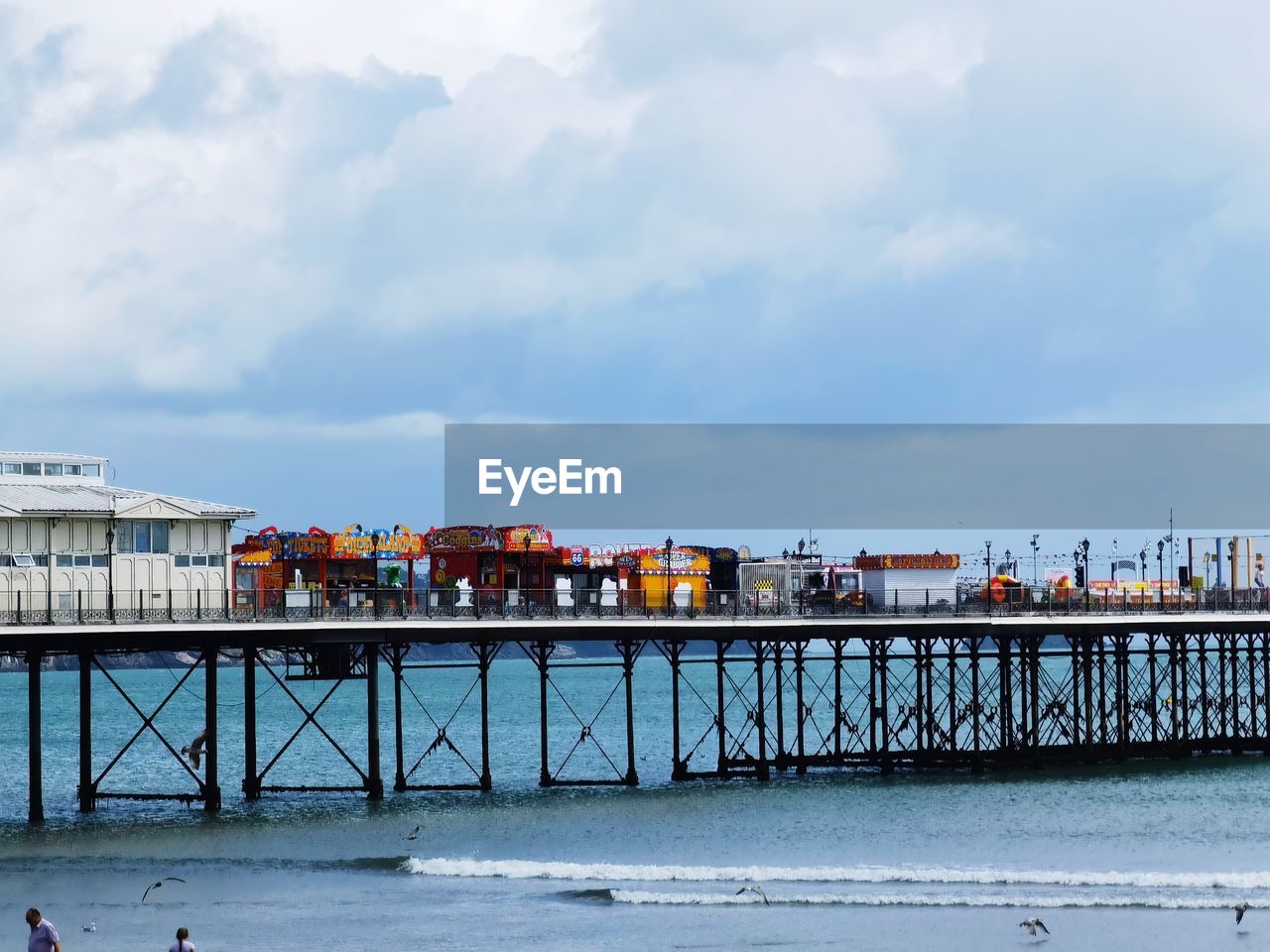 PIER OVER SEA BY BUILDINGS AGAINST SKY