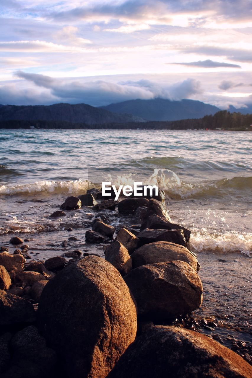 ROCKS ON BEACH AGAINST SKY AT SUNSET