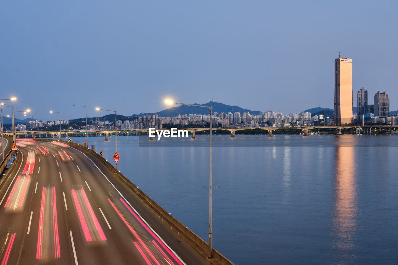 illuminated bridge over river in city at night