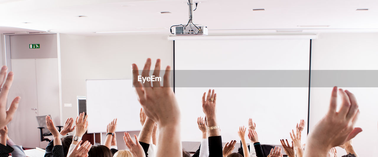 Cropped image of hands raised at seminar