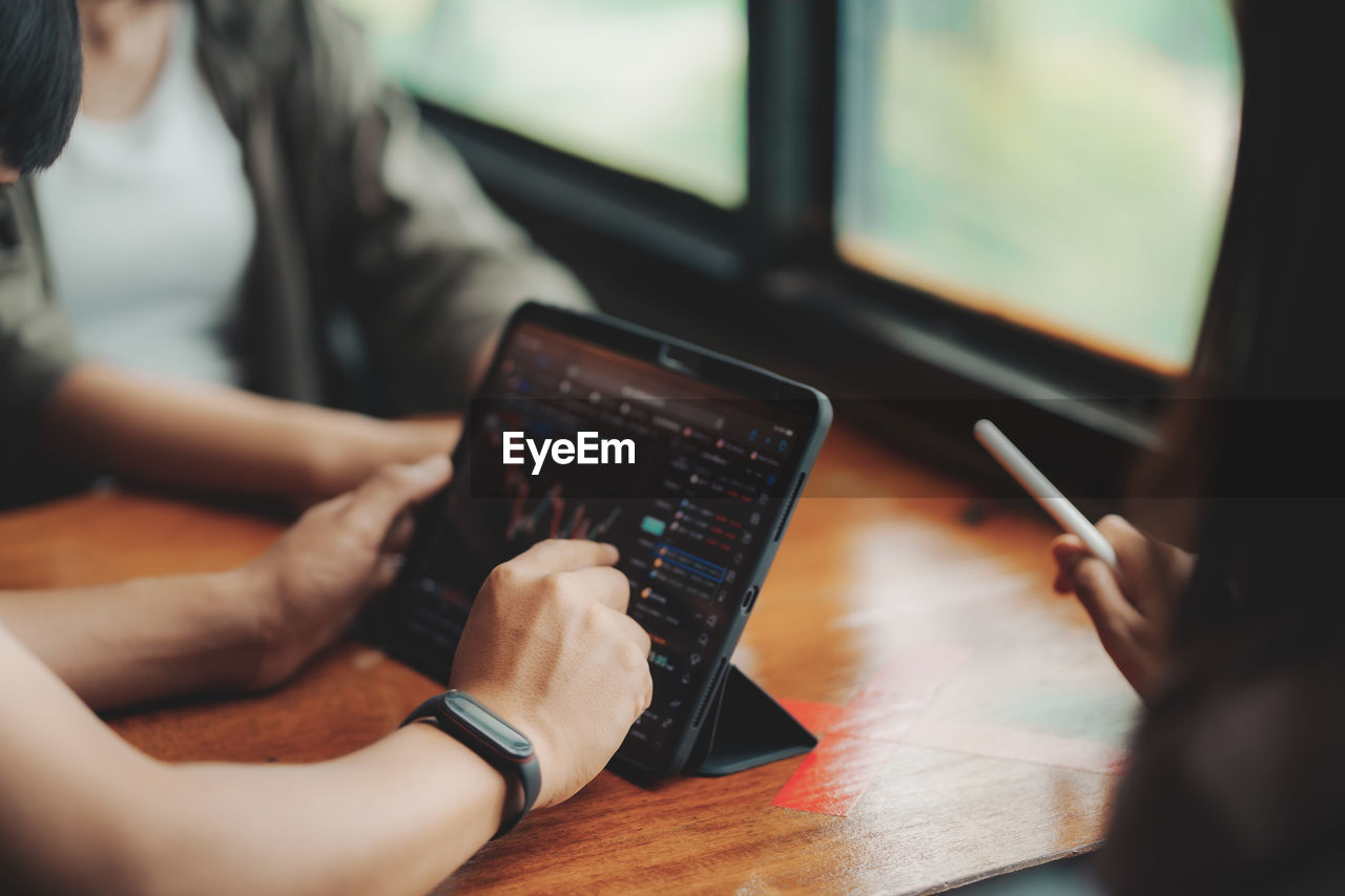 midsection of woman using digital tablet while sitting on table