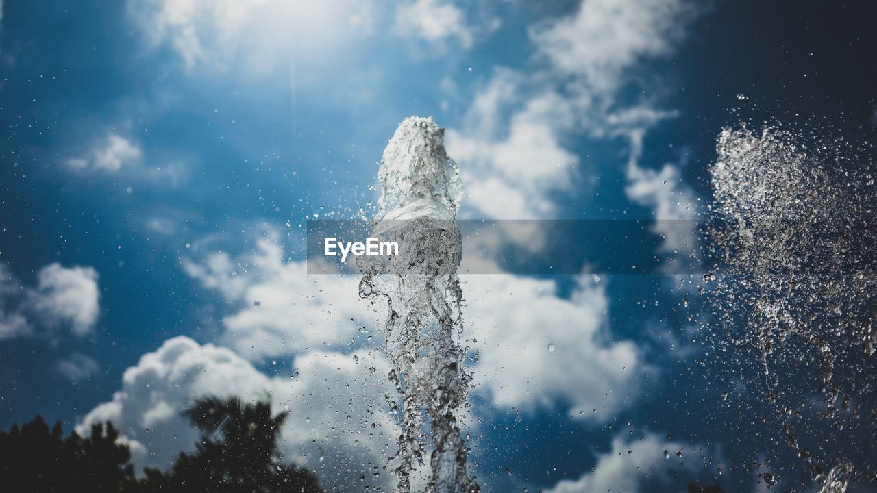 Close-up of fountain splashing water against cloudy sky