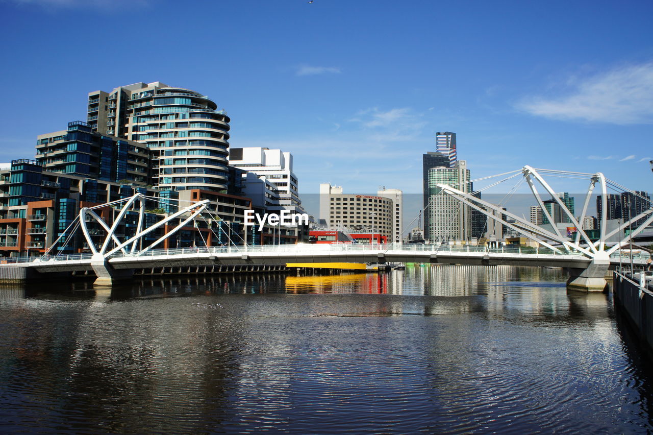 BRIDGE OVER RIVER WITH BUILDINGS IN BACKGROUND