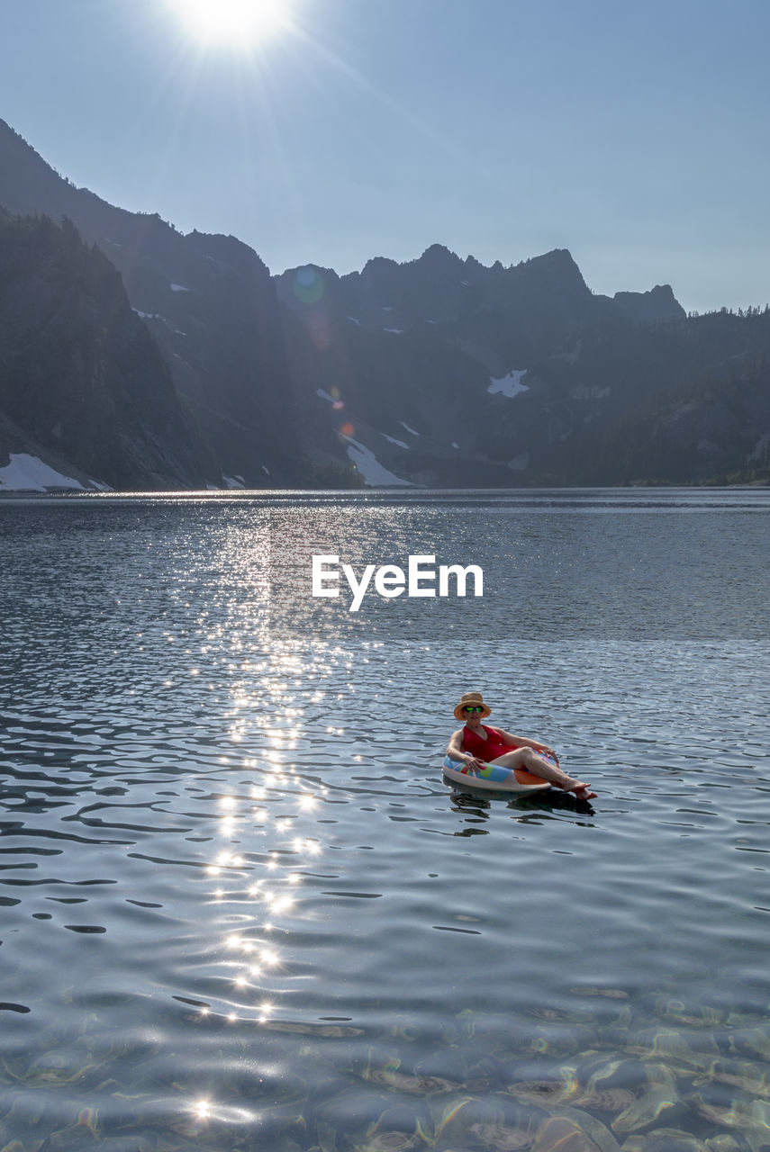 Woman on inflatable ring in lake against sky