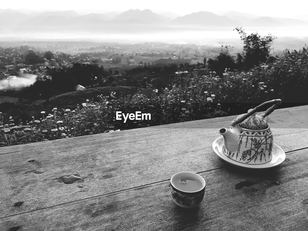 Teapot and tea on table against landscape