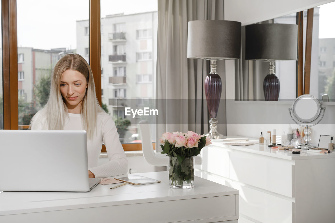 Woman works at the reception in a beauty salon. typing something on laptop and talks on the phone