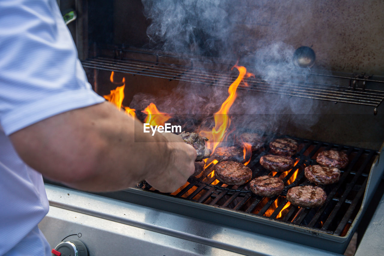 MIDSECTION OF MAN COOKING ON BARBECUE GRILL AT MARKET