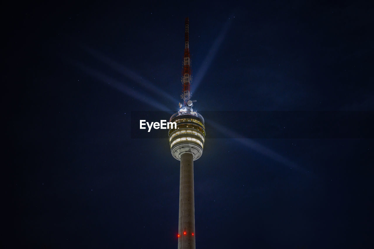 Stuttgart television tower against night sky with stars and light beams, germany