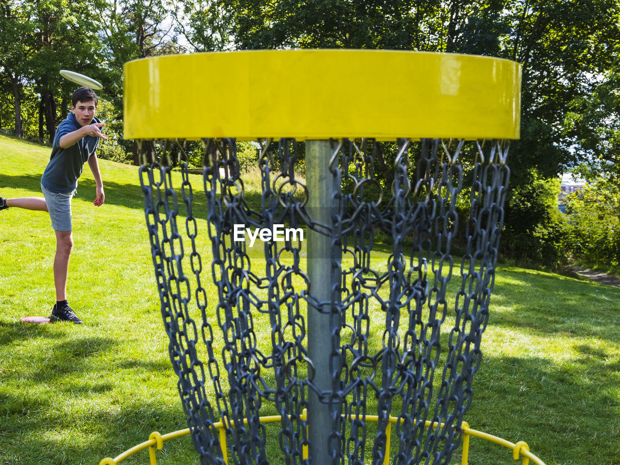 Teenage boy throwing frisbee to basket