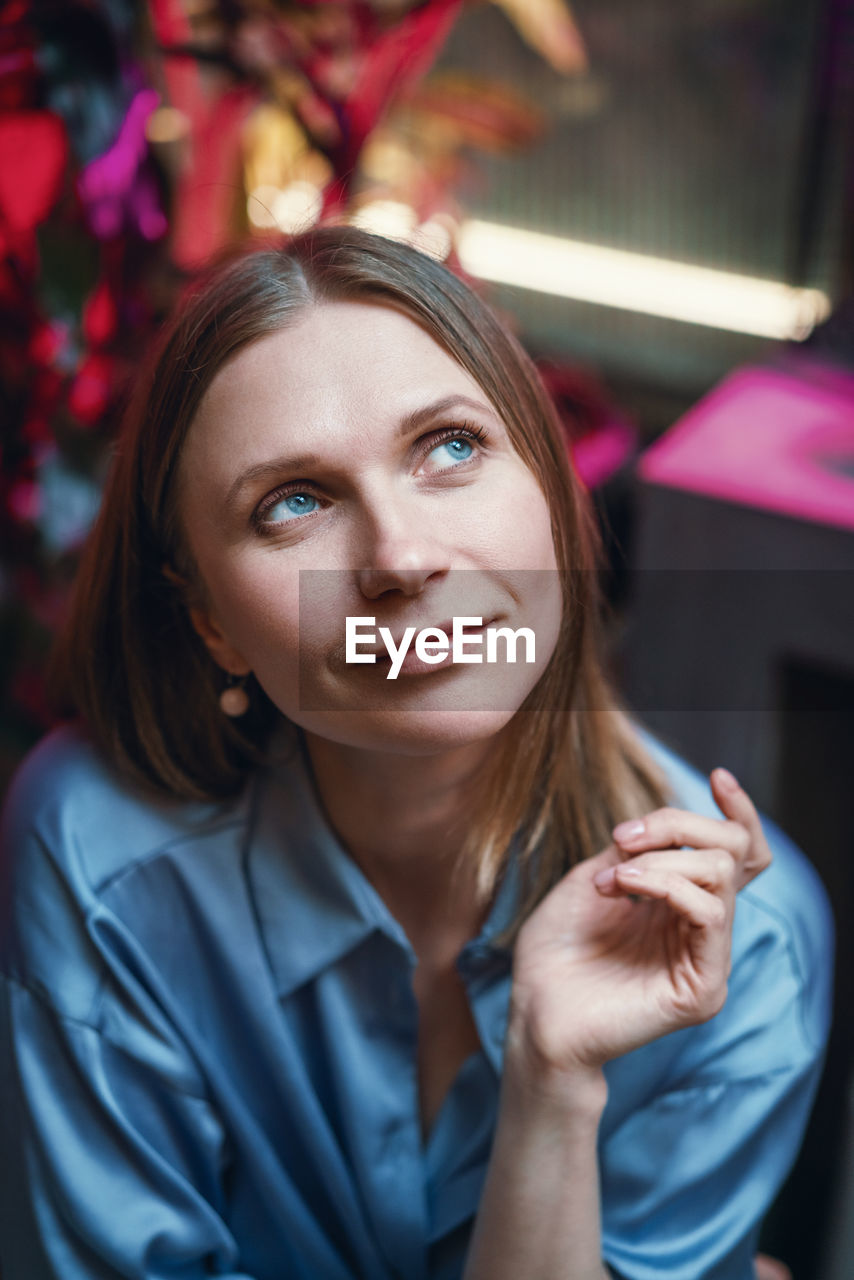 Woman sitting in a cafe at a table with a dreamy look