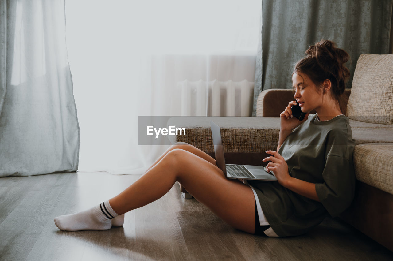 MIDSECTION OF WOMAN SITTING ON SOFA AT HOME