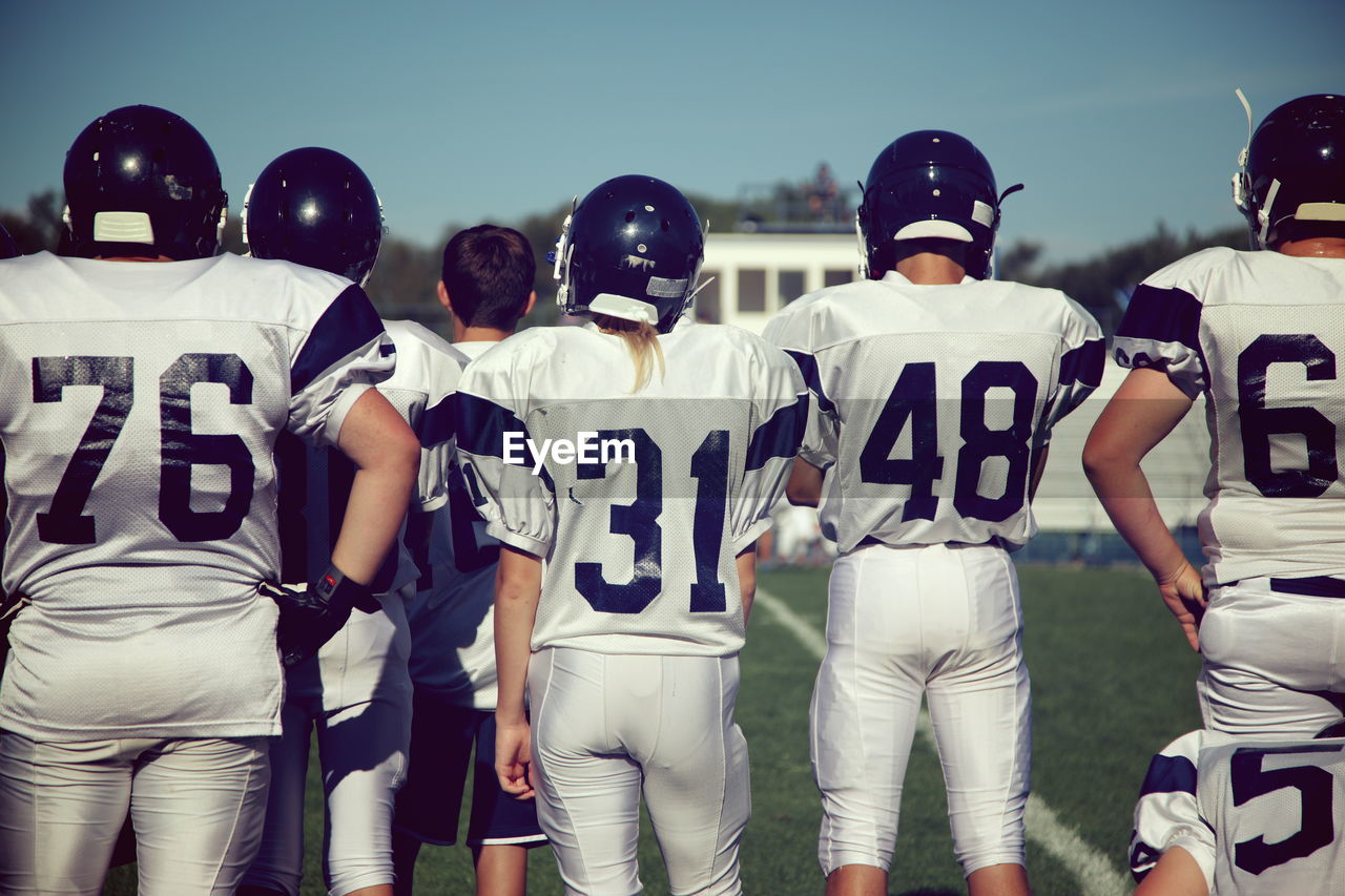 Rear view of female american football players standing on playing field