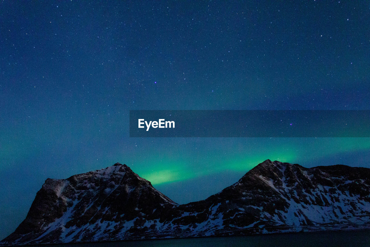 Scenic view of snowcapped mountains against sky at night