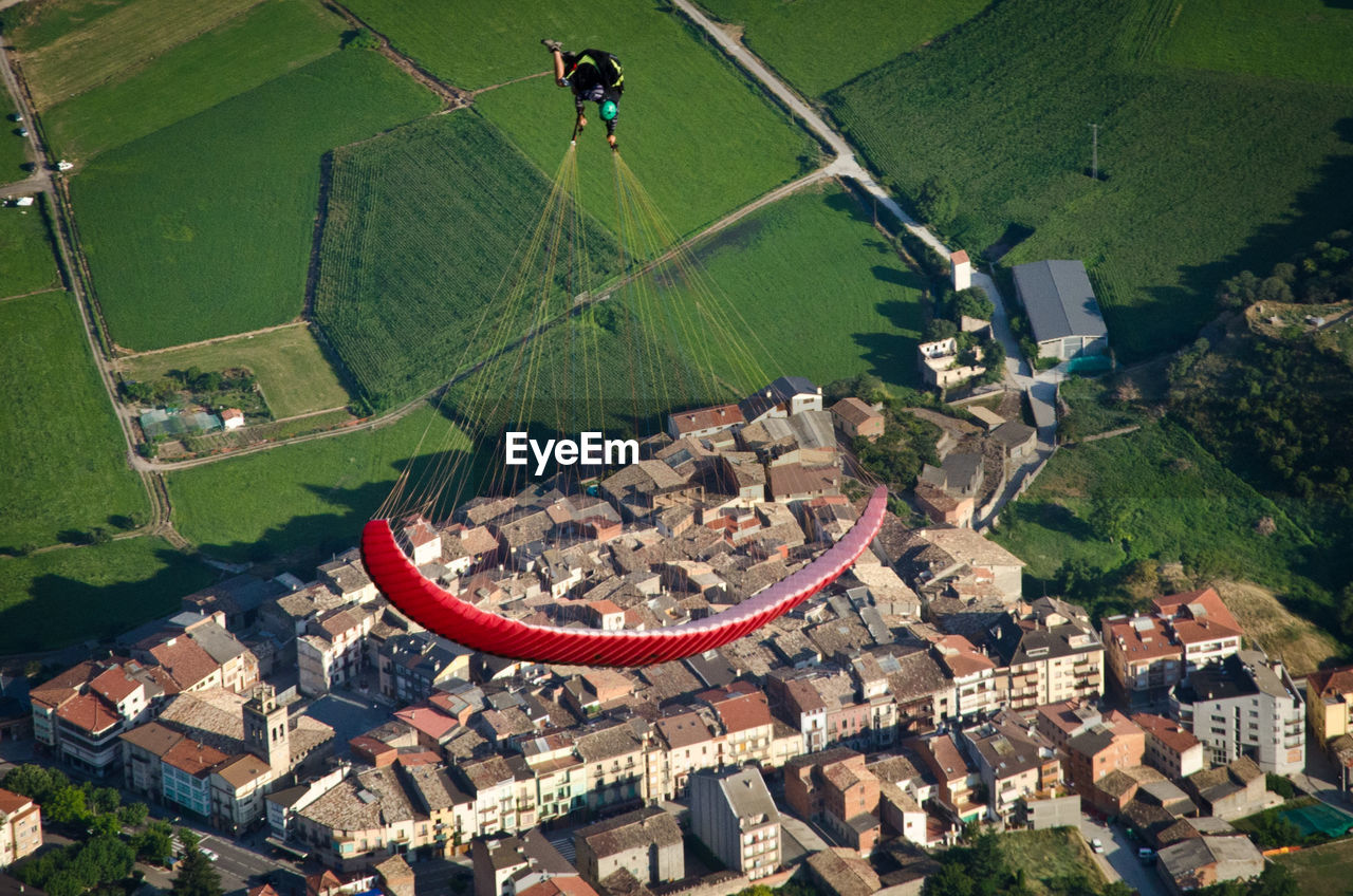 High angle view of man paragliding over townscape