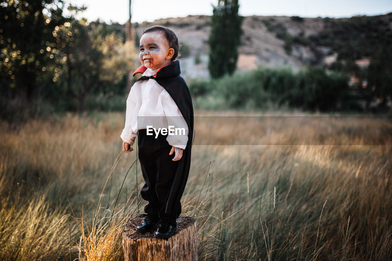 SIDE VIEW OF SMILING BOY STANDING ON LAND