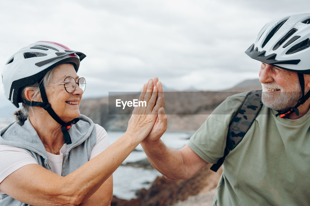 adult, men, two people, helmet, headwear, sports, sports helmet, leisure activity, togetherness, mature adult, senior adult, seniors, activity, bicycle helmet, emotion, nature, smiling, protection, lifestyles, happiness, day, sports equipment, exercising, sports clothing, transportation, cycling, outdoors, security, waist up, personal protective equipment, women, portrait, vitality, headshot, person, adventure, mountain, enjoyment, positive emotion, focus on foreground, bicycle, bonding, glasses