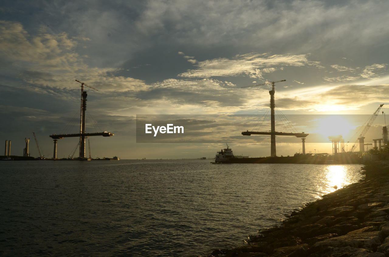 SILHOUETTE CRANES AGAINST SKY DURING SUNSET