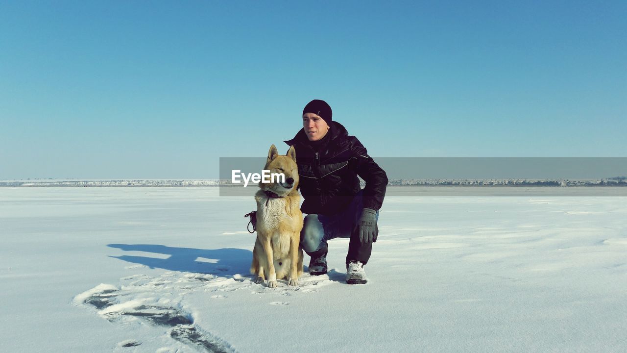 Portrait of man with dog standing on snow