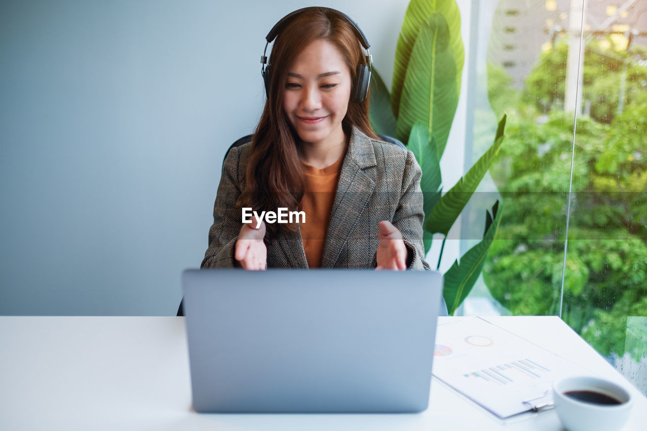 portrait of young woman using laptop while sitting on table