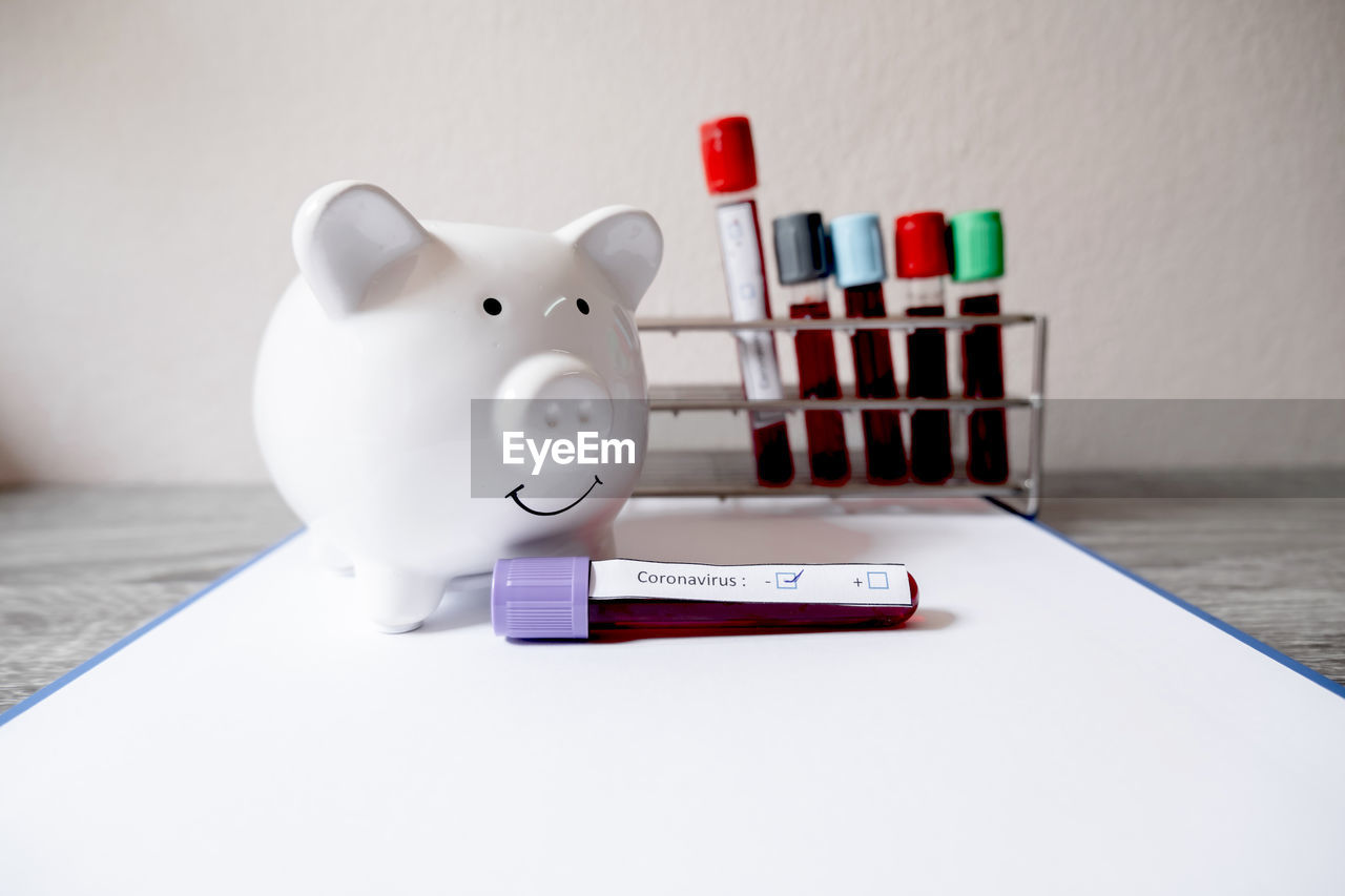 Close-up of piggy bank with blood samples on table