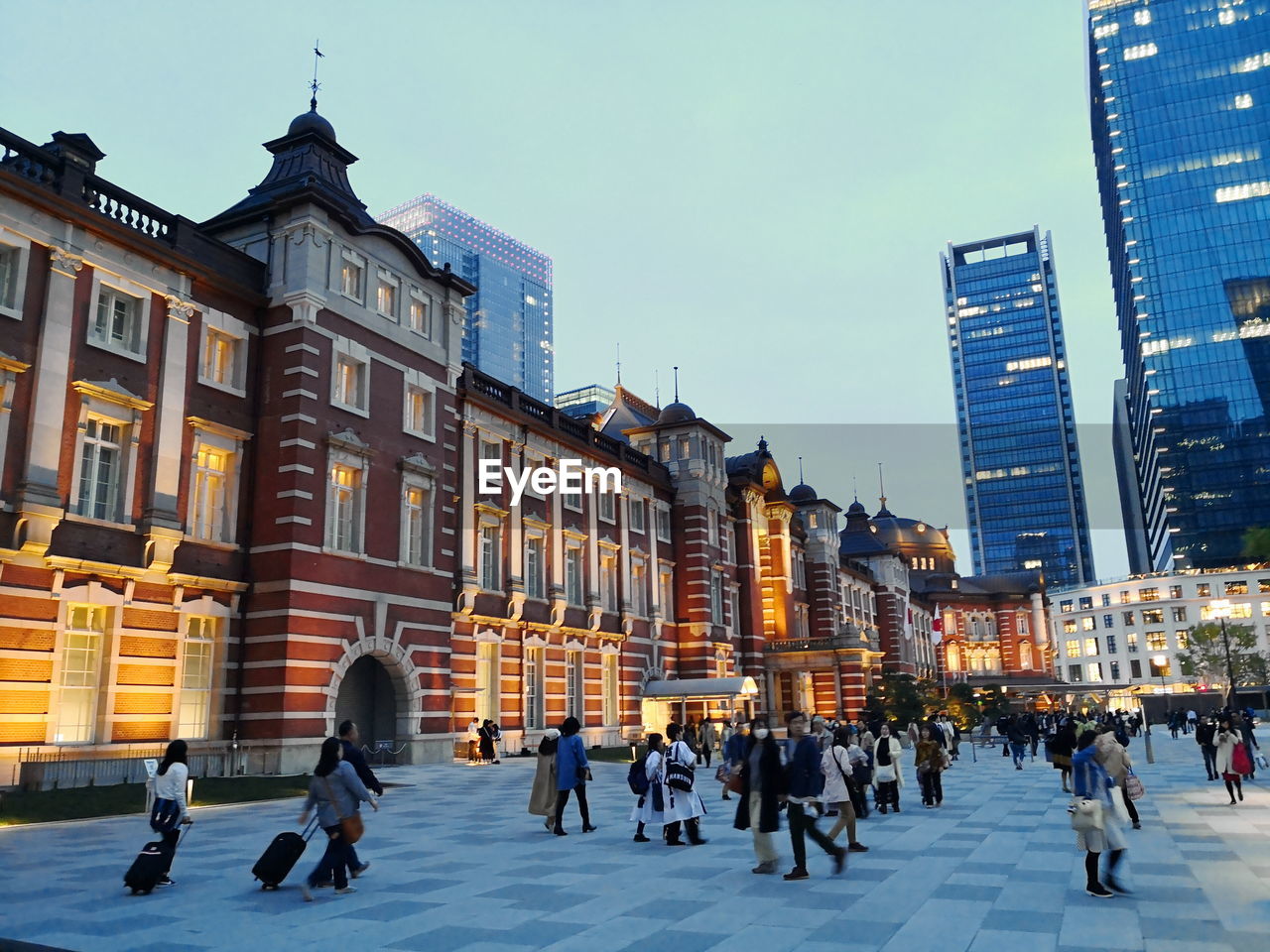 GROUP OF PEOPLE WALKING ON STREET AGAINST BUILDINGS