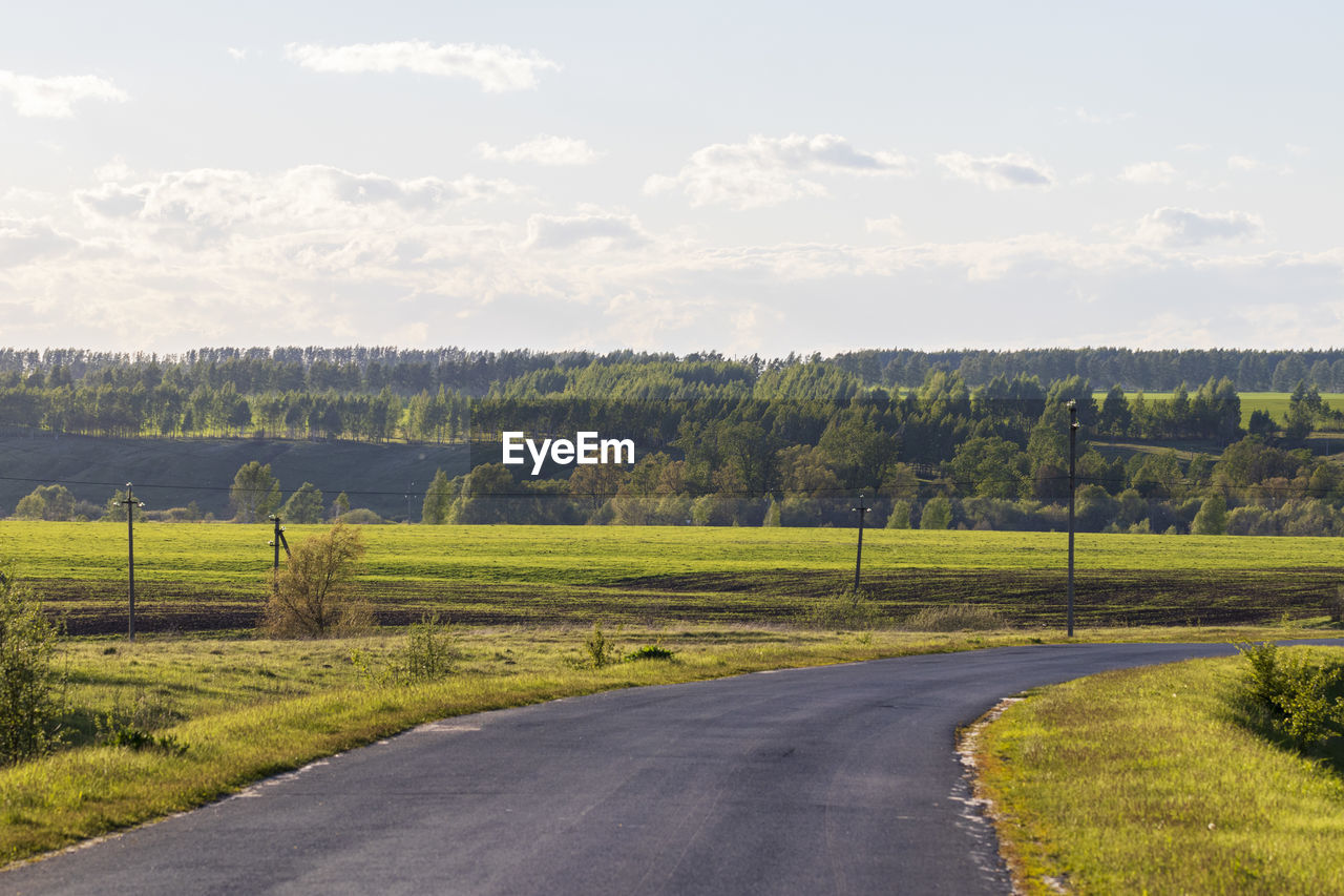 landscape, plant, environment, sky, road, nature, land, rural area, hill, scenics - nature, beauty in nature, tree, field, rural scene, transportation, cloud, no people, grass, tranquility, plain, agriculture, green, horizon, tranquil scene, day, non-urban scene, growth, outdoors, country road, sunlight, travel, prairie, highway, the way forward, farm, idyllic